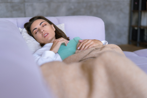 women sleeping on sofa with heating pad